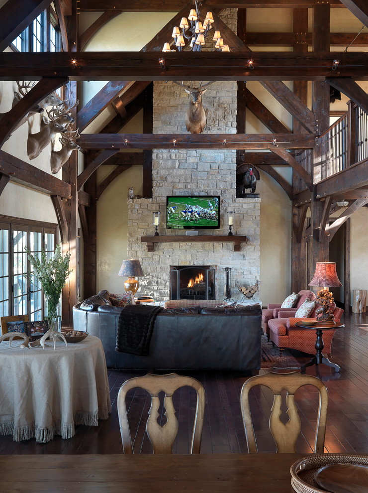 Photo of a large rustic open plan games room in St Louis with beige walls, medium hardwood flooring, a standard fireplace, a stone fireplace surround and a wall mounted tv.