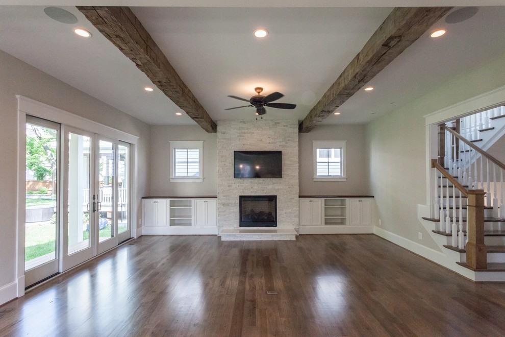 This is an example of a country games room in DC Metro with grey walls, medium hardwood flooring, a standard fireplace, a stone fireplace surround, a wall mounted tv and brown floors.