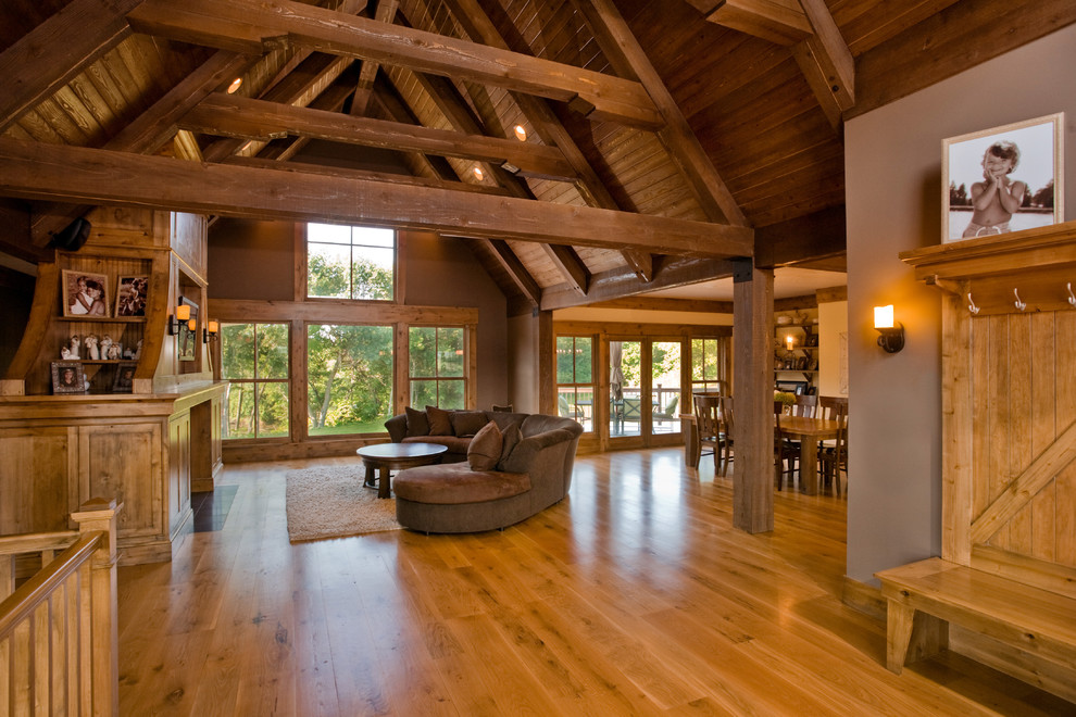 Diseño de sala de estar abierta de estilo de casa de campo con paredes marrones, suelo de madera en tonos medios y todas las chimeneas