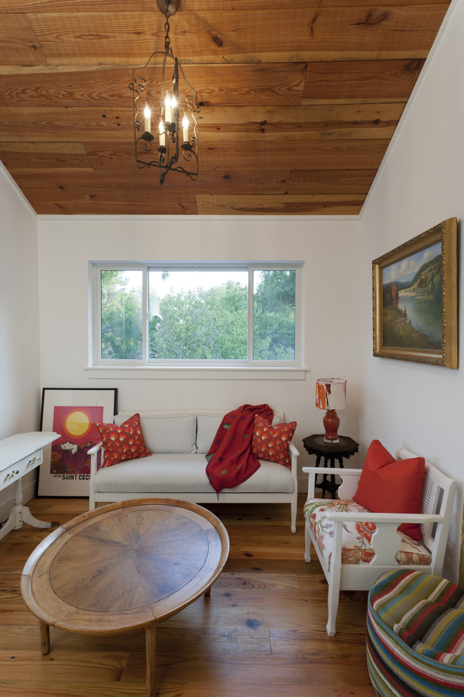 Réalisation d'une salle de séjour champêtre avec un mur blanc et un sol en bois brun.