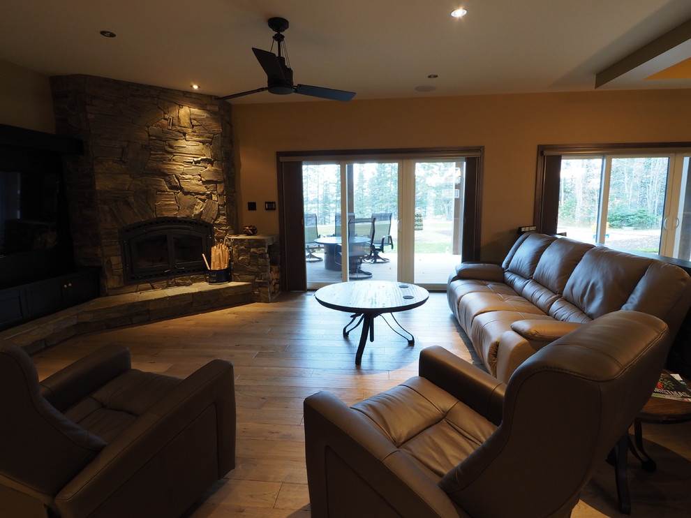 Ejemplo de sala de estar abierta de estilo de casa de campo grande con paredes beige, estufa de leña, marco de chimenea de piedra, pared multimedia, suelo marrón y suelo de madera clara