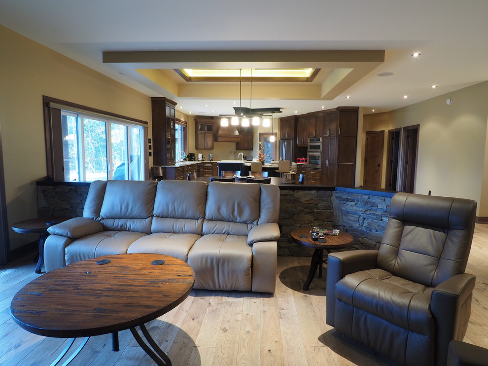 Exemple d'une grande salle de séjour nature ouverte avec un mur beige, un poêle à bois, un manteau de cheminée en pierre, un téléviseur encastré, un sol marron et parquet clair.