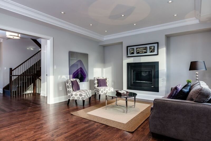 Modelo de sala de estar abierta clásica renovada con suelo de madera en tonos medios, marco de chimenea de piedra y televisor colgado en la pared