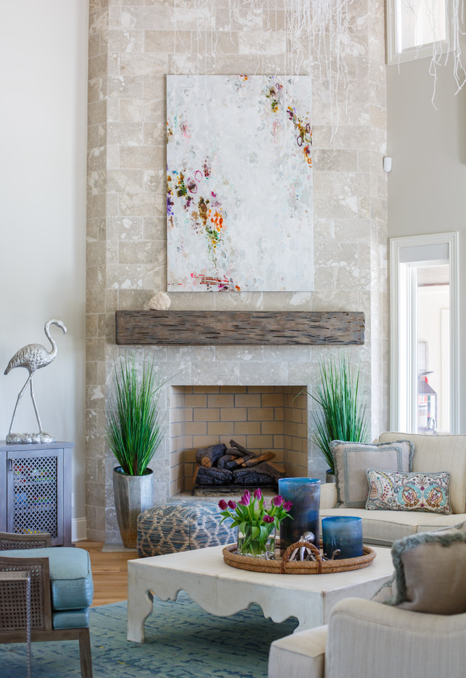 Diseño de salón costero con paredes beige, suelo de madera en tonos medios, chimenea de esquina, marco de chimenea de piedra y televisor colgado en la pared