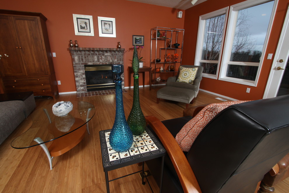 Источник вдохновения для домашнего уюта: большая открытая гостиная комната в стиле фьюжн с оранжевыми стенами, полом из бамбука, стандартным камином и фасадом камина из кирпича