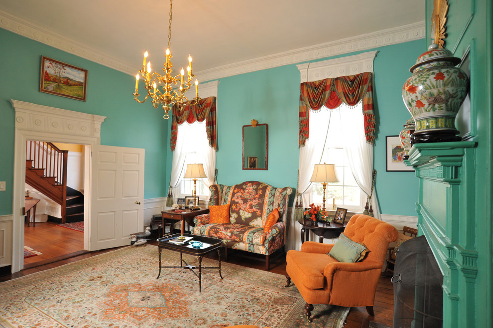 Réalisation d'une salle de séjour tradition fermée avec un mur vert, parquet foncé, une cheminée standard, un manteau de cheminée en plâtre et un sol marron.