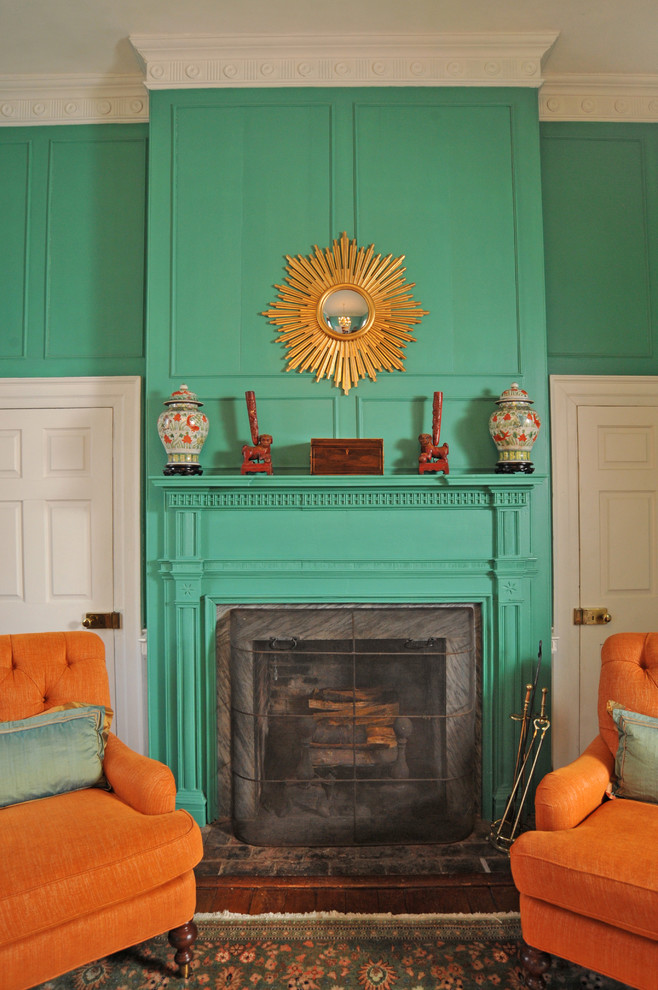 Foto di un soggiorno tradizionale con pareti verdi, parquet scuro, camino classico, cornice del camino in intonaco, nessuna TV e pavimento marrone