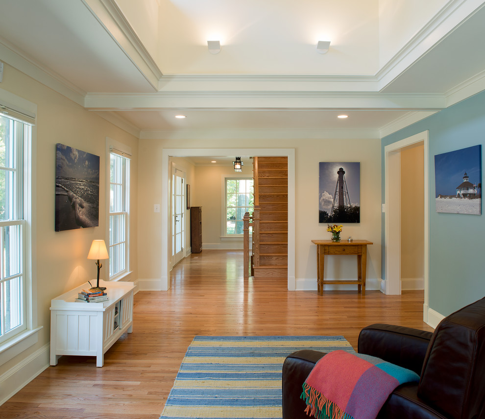 Foto de sala de estar cerrada costera de tamaño medio sin chimenea y televisor con paredes azules y suelo de madera clara