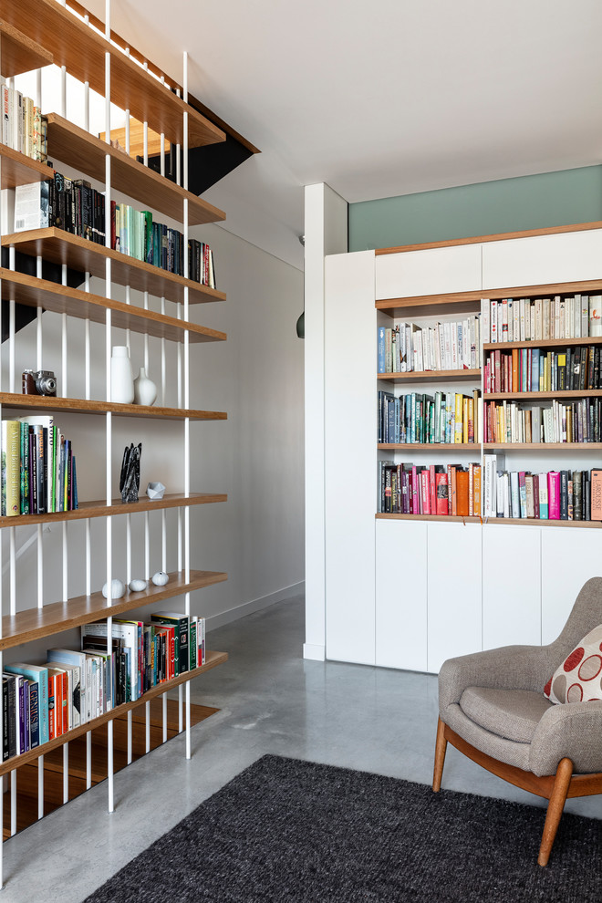 На фото: двухуровневая гостиная комната среднего размера в современном стиле с с книжными шкафами и полками, белыми стенами, бетонным полом и серым полом