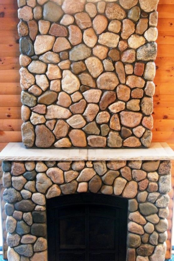 Exemple d'une salle de séjour montagne ouverte avec un mur marron, une cheminée standard et un manteau de cheminée en pierre.