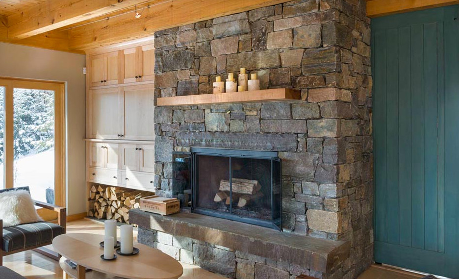 Aménagement d'une grande salle de séjour mansardée ou avec mezzanine scandinave avec un mur beige, parquet clair, une cheminée standard et un manteau de cheminée en pierre.
