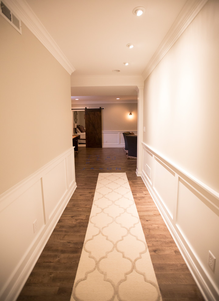 Exemple d'un grand couloir chic avec un sol en vinyl, un mur beige et un sol marron.