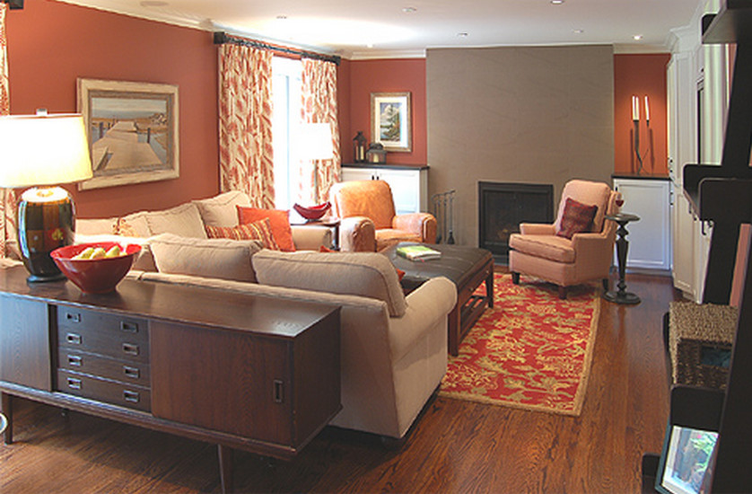 Modelo de sala de estar cerrada actual de tamaño medio con parades naranjas, suelo de madera en tonos medios, todas las chimeneas, marco de chimenea de baldosas y/o azulejos y pared multimedia