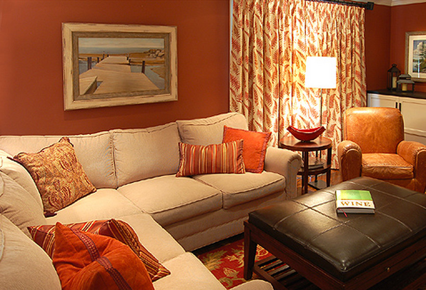 Cette photo montre une salle de séjour tendance de taille moyenne et fermée avec un mur orange, un sol en bois brun, une cheminée standard, un manteau de cheminée en carrelage et un téléviseur encastré.