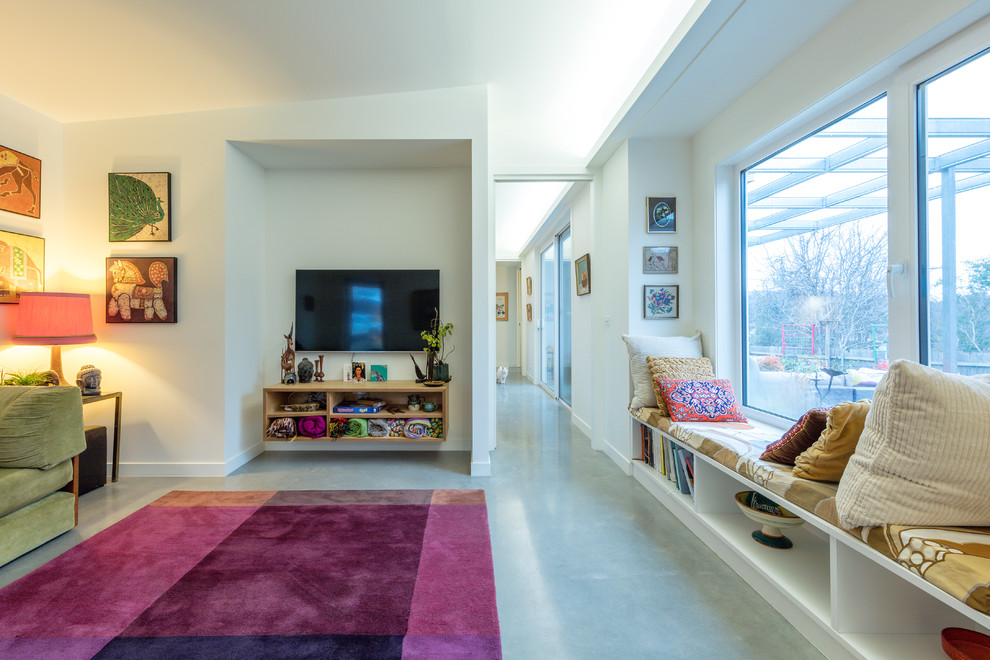 Ispirazione per un piccolo soggiorno design aperto con pareti bianche, pavimento in cemento, TV autoportante e pavimento grigio