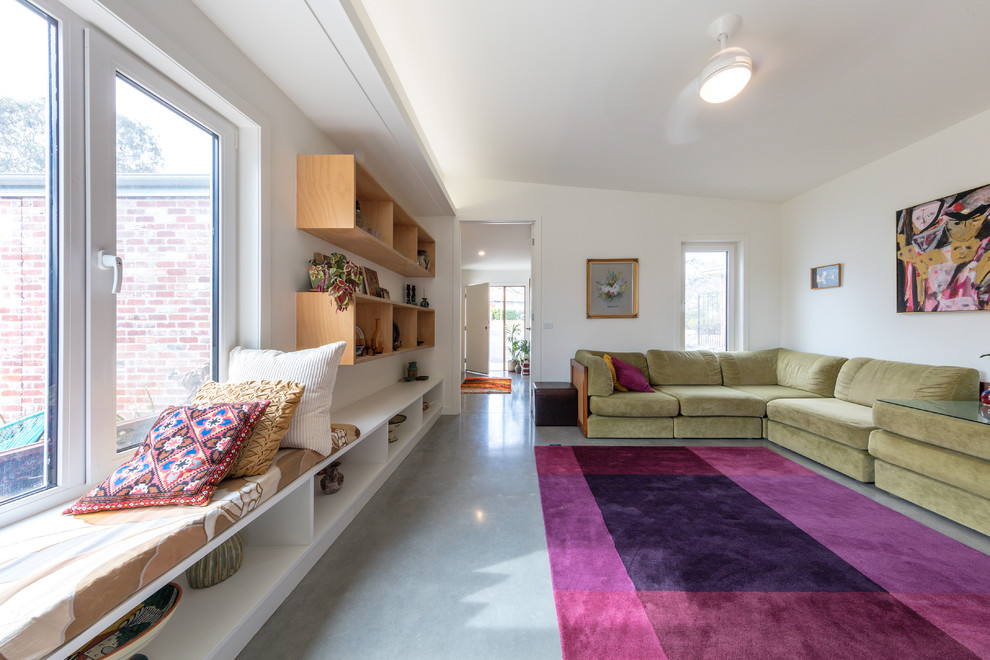 Источник вдохновения для домашнего уюта: маленькая открытая гостиная комната в современном стиле с белыми стенами, бетонным полом, отдельно стоящим телевизором и серым полом для на участке и в саду