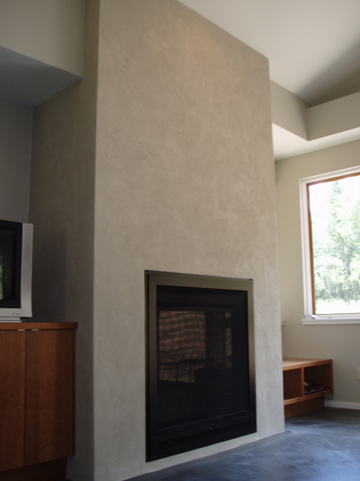 デンバーにある低価格の広いコンテンポラリースタイルのおしゃれなオープンリビング (ベージュの壁、コンクリートの床、両方向型暖炉、漆喰の暖炉まわり、テレビなし) の写真