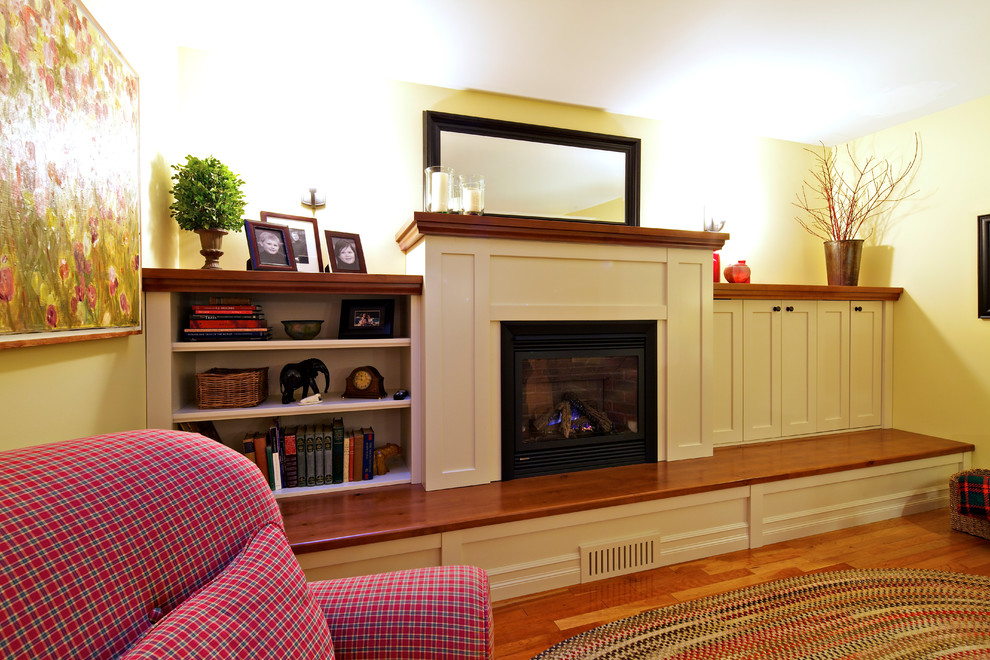 Источник вдохновения для домашнего уюта: изолированная гостиная комната среднего размера в стиле неоклассика (современная классика) с желтыми стенами, паркетным полом среднего тона, стандартным камином и фасадом камина из дерева без телевизора