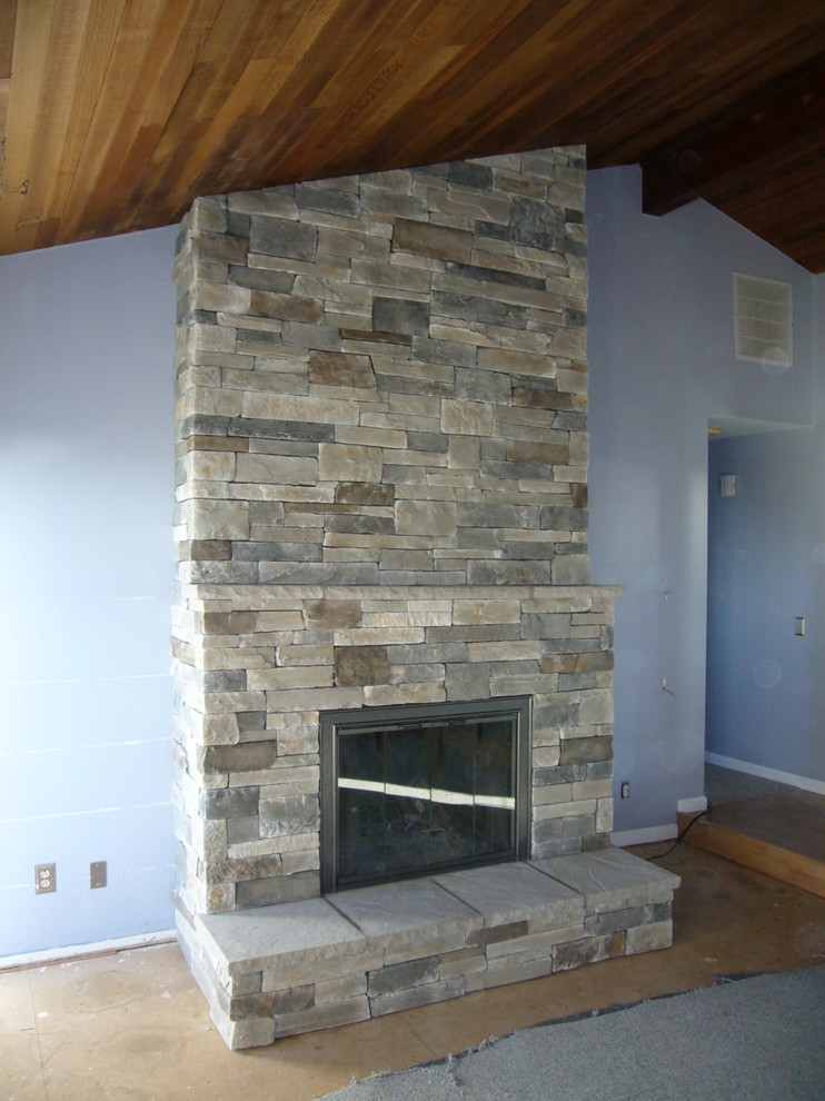 На фото: гостиная комната в классическом стиле с стандартным камином и фасадом камина из камня