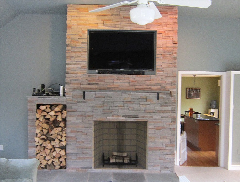 Пример оригинального дизайна: гостиная комната в стиле неоклассика (современная классика) с серыми стенами, стандартным камином, фасадом камина из камня и телевизором на стене