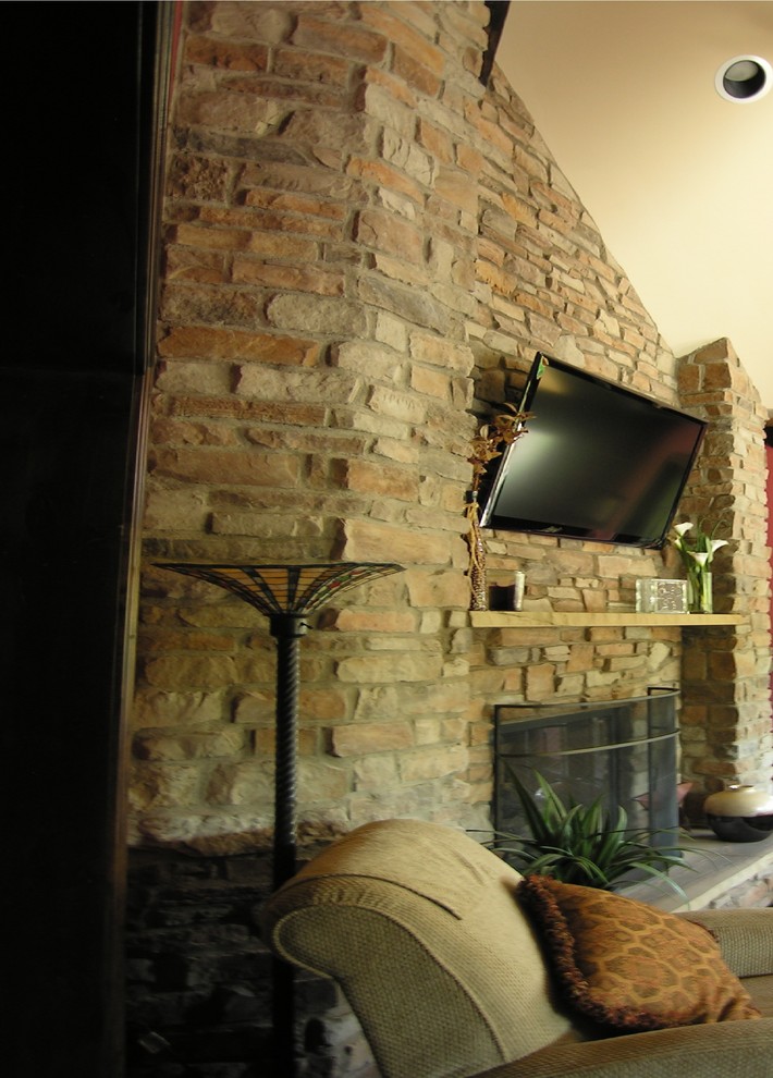 Diseño de sala de estar con biblioteca tradicional de tamaño medio con todas las chimeneas, marco de chimenea de piedra y televisor colgado en la pared
