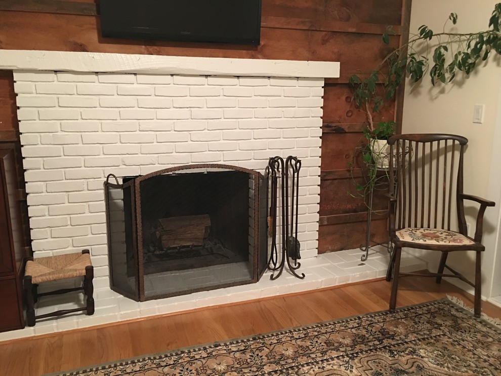 ニューヨークにある低価格のカントリー風のおしゃれなファミリールーム (ライブラリー、淡色無垢フローリング、標準型暖炉、レンガの暖炉まわり、壁掛け型テレビ) の写真