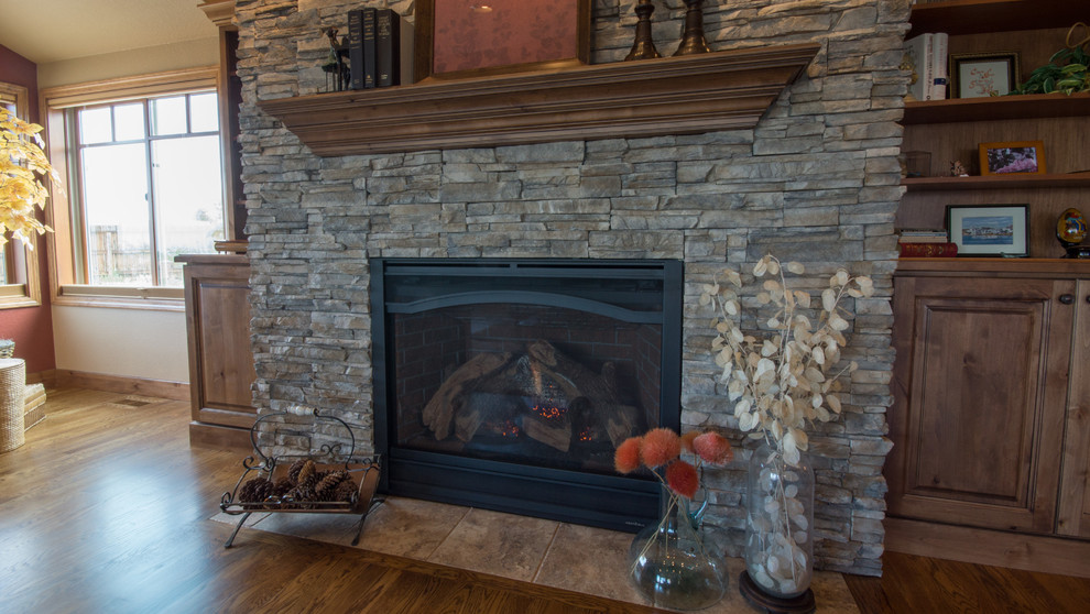 Inspiration for a large timeless open concept medium tone wood floor family room remodel in Denver with brown walls, a standard fireplace, a stone fireplace and a media wall