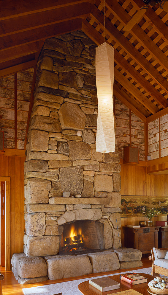 Exemple d'une grande salle de séjour montagne fermée avec un mur multicolore, un sol en bois brun, une cheminée standard, un manteau de cheminée en pierre et aucun téléviseur.