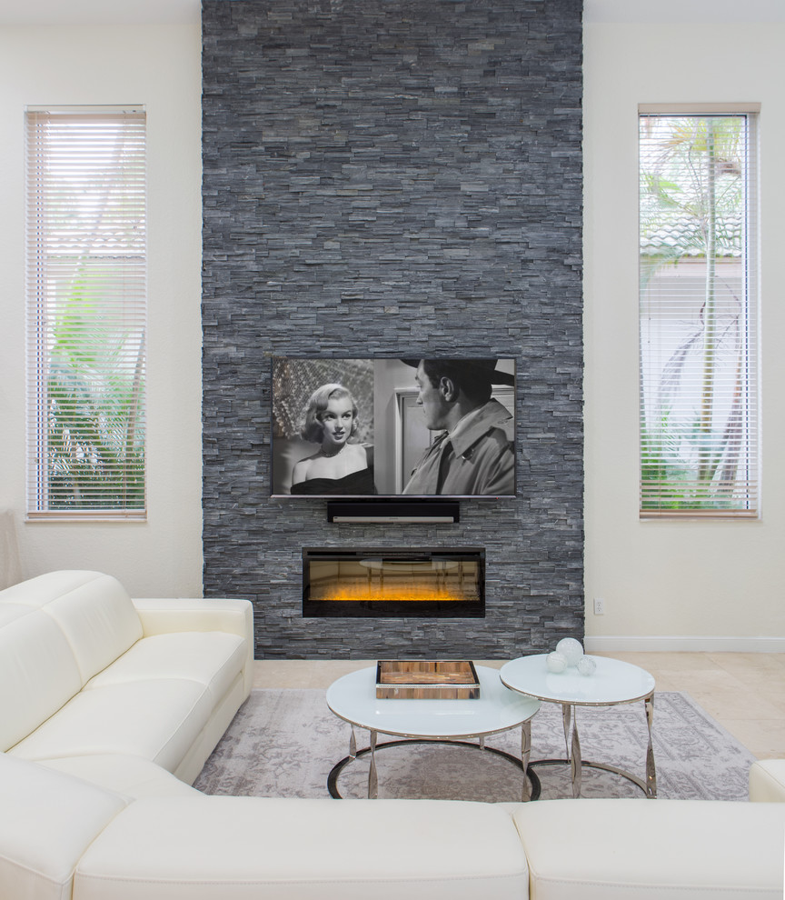 マイアミにあるお手頃価格の広いコンテンポラリースタイルのおしゃれなオープンリビング (白い壁、大理石の床、横長型暖炉、石材の暖炉まわり、壁掛け型テレビ、ベージュの床) の写真
