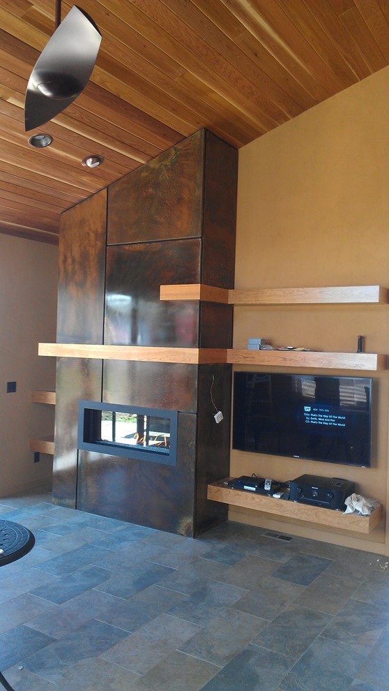 Photo of an industrial games room in Denver with beige walls, slate flooring, a standard fireplace, a metal fireplace surround and a wall mounted tv.