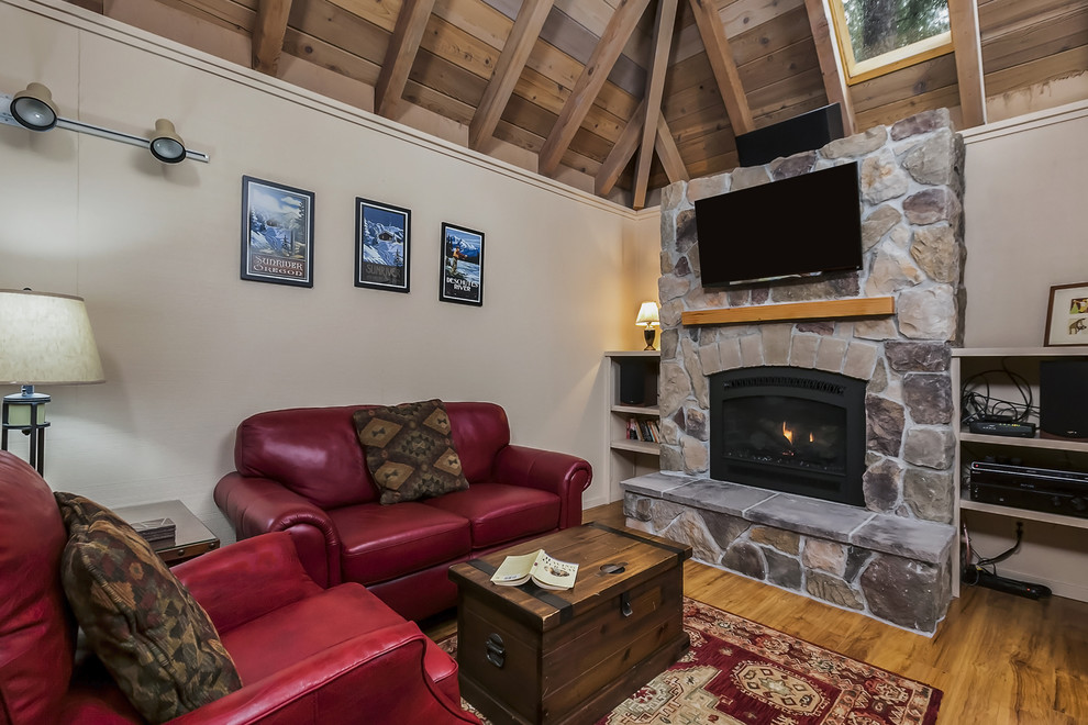 Cette photo montre une petite salle de séjour craftsman ouverte avec un mur beige, parquet clair, une cheminée standard et un manteau de cheminée en pierre.