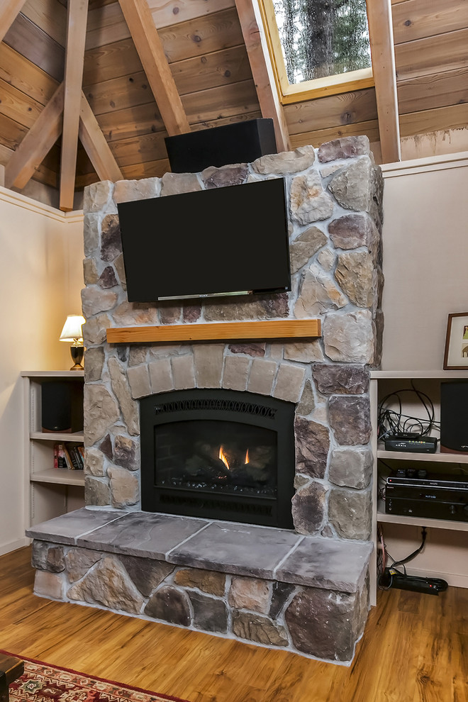 Exemple d'une petite salle de séjour craftsman ouverte avec un mur beige, parquet clair, une cheminée standard et un manteau de cheminée en pierre.