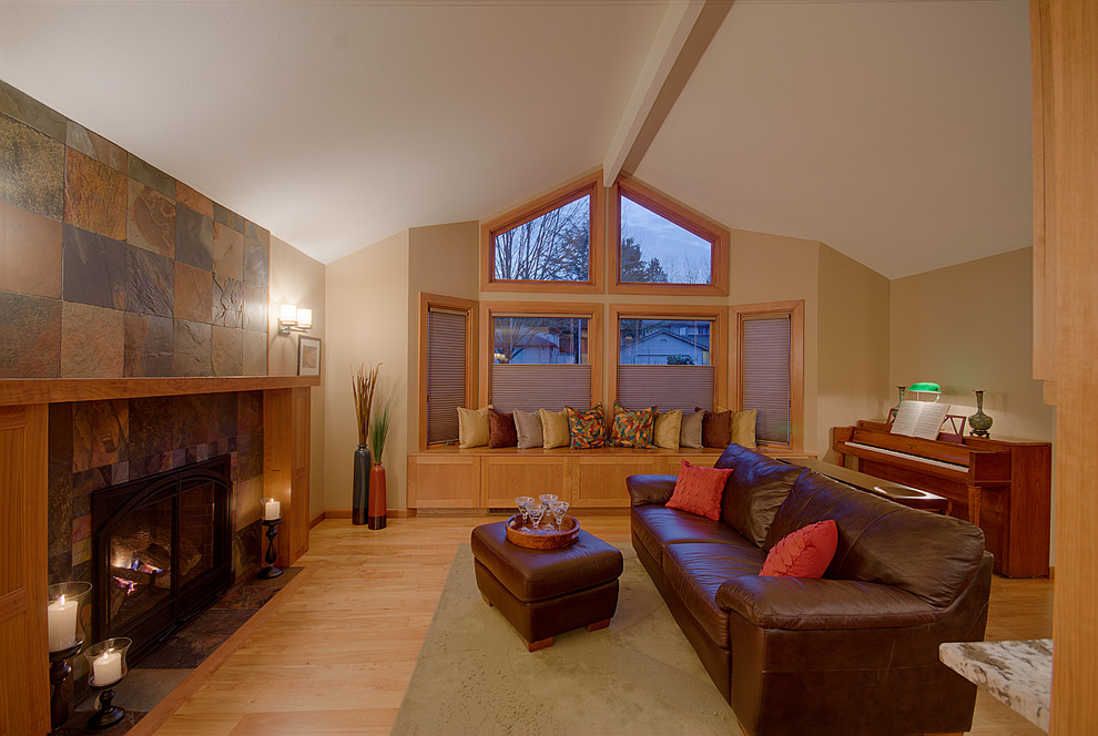 Exemple d'une grande salle de séjour tendance fermée avec un manteau de cheminée en pierre, un mur beige, parquet clair et une cheminée standard.