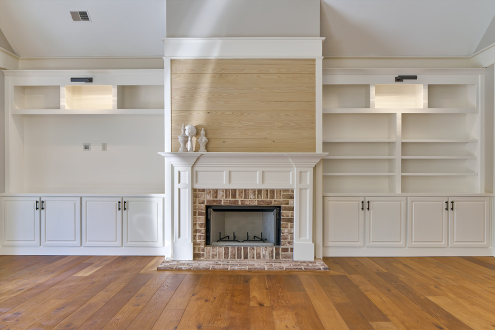 Example of a large transitional medium tone wood floor family room library design in Charleston with white walls, a standard fireplace, a brick fireplace and a media wall