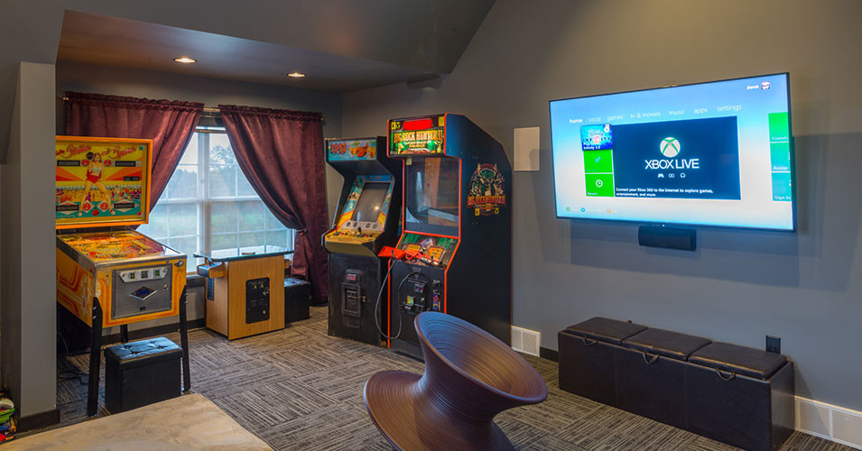 Foto de sala de juegos en casa cerrada de estilo americano grande con paredes grises, moqueta y televisor colgado en la pared