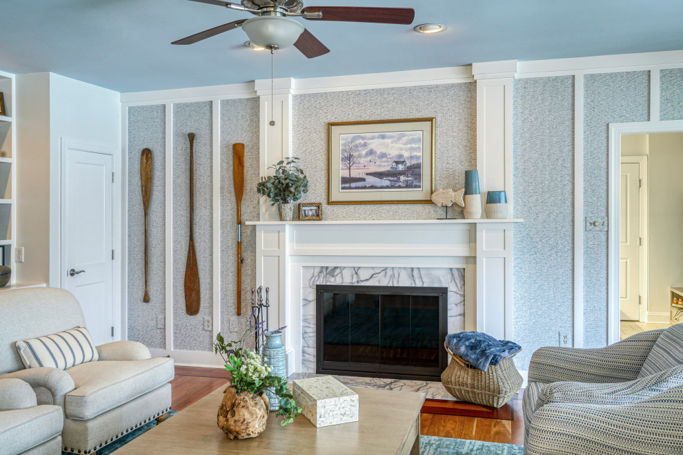 На фото: гостиная комната в морском стиле с серыми стенами, паркетным полом среднего тона, стандартным камином, коричневым полом и панелями на части стены с
