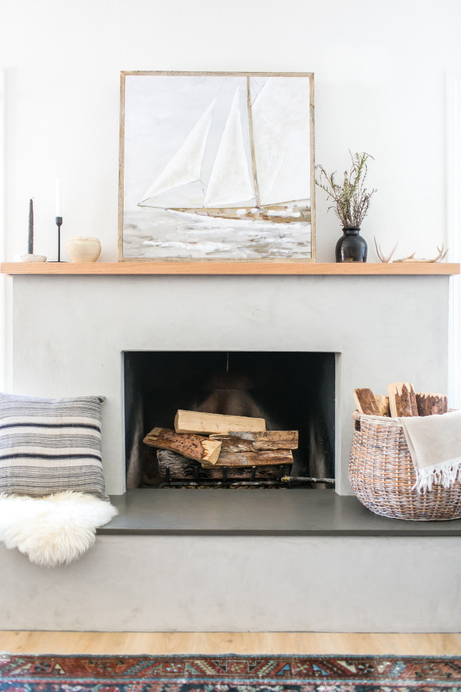 Inspiration for a beach style living room in San Diego with black walls, a standard fireplace and a plastered fireplace surround.