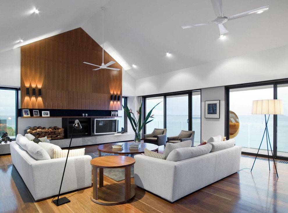 Idée de décoration pour une grande salle de séjour design ouverte avec un mur blanc, un sol en bois brun, une cheminée standard, un manteau de cheminée en pierre et un téléviseur indépendant.