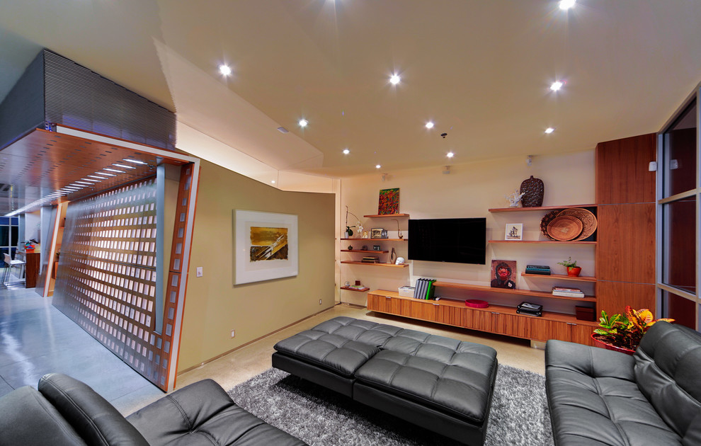 Cette photo montre une salle de séjour tendance ouverte avec un mur beige, sol en béton ciré et un téléviseur fixé au mur.