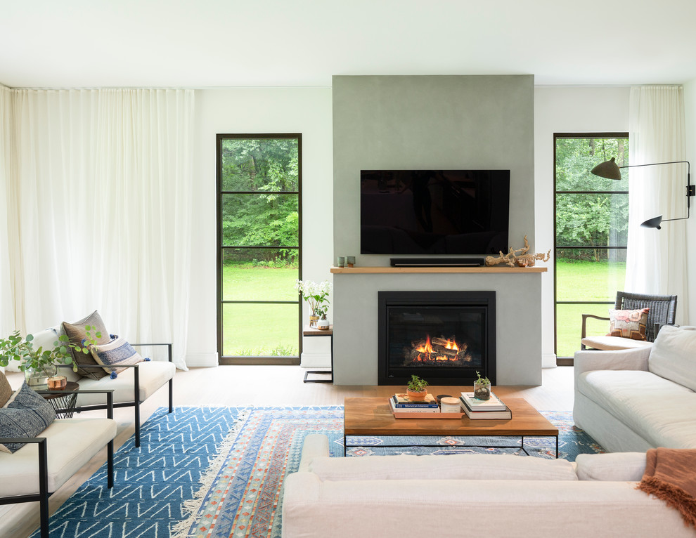 Пример оригинального дизайна: гостиная комната в стиле неоклассика (современная классика) с белыми стенами, светлым паркетным полом, стандартным камином, телевизором на стене и ковром на полу