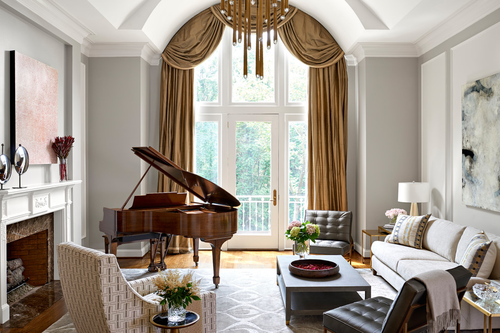 Cette image montre une grande salle de séjour traditionnelle avec une salle de musique, un sol en bois brun, une cheminée standard, un manteau de cheminée en pierre, aucun téléviseur et un mur gris.