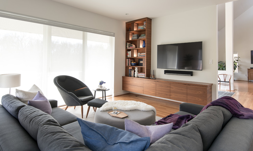Foto de sala de estar cerrada moderna de tamaño medio sin chimenea con paredes blancas, suelo de madera en tonos medios, televisor colgado en la pared y suelo marrón