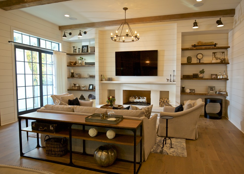 Источник вдохновения для домашнего уюта: изолированная гостиная комната среднего размера в стиле рустика с белыми стенами, светлым паркетным полом, стандартным камином, фасадом камина из дерева, телевизором на стене и ковром на полу