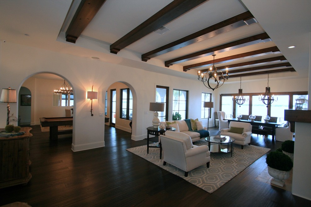 Large mediterranean open plan games room in Tampa with white walls, dark hardwood flooring, a standard fireplace, a plastered fireplace surround, no tv and brown floors.