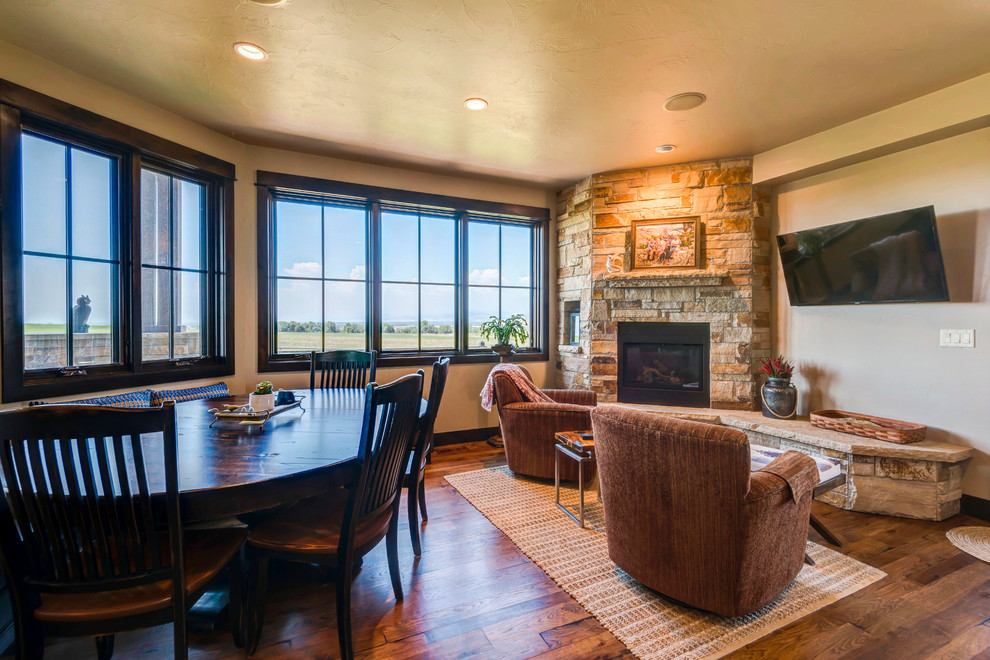 Photo of a medium sized classic open plan games room in Denver with beige walls, medium hardwood flooring, a corner fireplace, a stone fireplace surround, a wall mounted tv and brown floors.