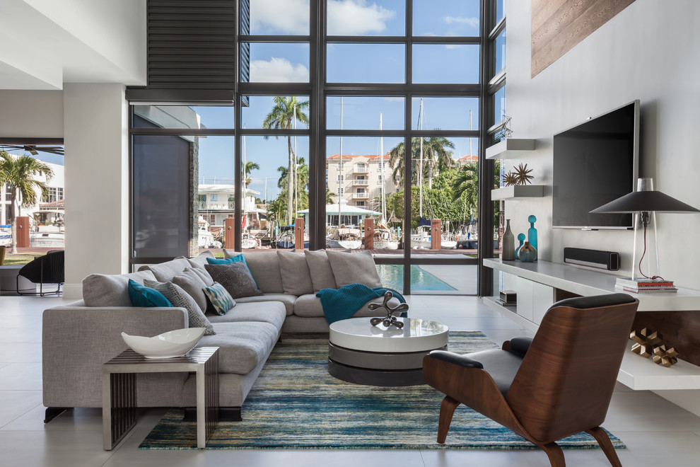 Offenes Modernes Wohnzimmer mit weißer Wandfarbe, TV-Wand und grauem Boden in Miami