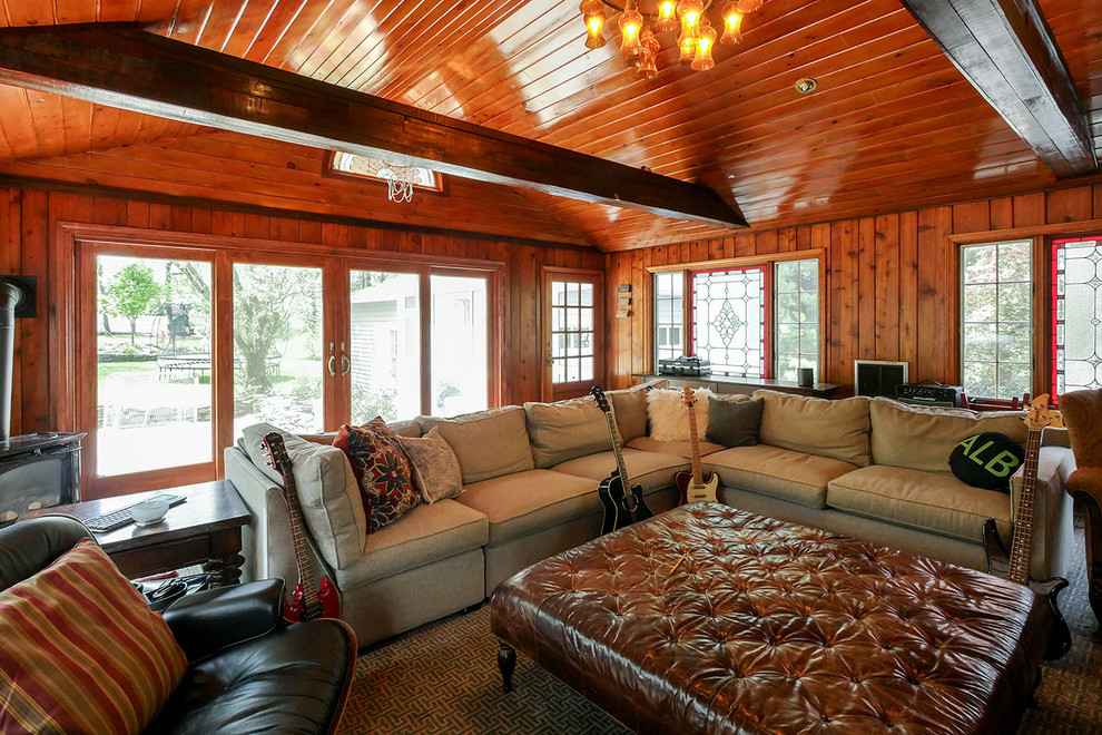 Esempio di un grande soggiorno chiuso con sala della musica, pareti marroni, moquette, stufa a legna, TV a parete e pavimento marrone
