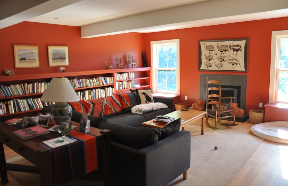 Mittelgroßes Landhausstil Wohnzimmer mit roter Wandfarbe, hellem Holzboden, Kamin und Kaminumrandung aus Stein in New York