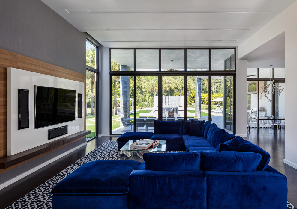 Imagen de sala de estar contemporánea sin chimenea con paredes grises, suelo de madera oscura y pared multimedia