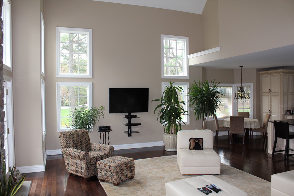 Foto de sala de estar abierta clásica grande con paredes beige, suelo de madera oscura y televisor colgado en la pared